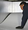 A contractor installing TerraBlock floor insulation in a Cedar Falls crawl space
