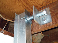 Securing the i-beam system to the top of the floor joist in a foundation wall repair in Cedar Falls.